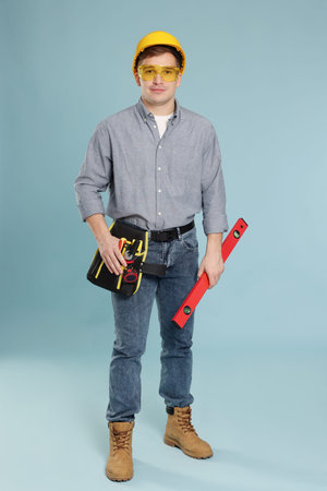 Professional builder with tools on light blue background