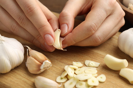 Woman peeling fresh garlic at table, closeupの写真素材