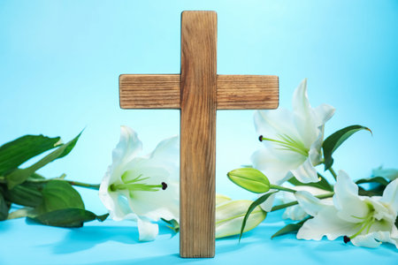 Easter. Wooden cross and beautiful lily flowers on light blue background, closeupの写真素材