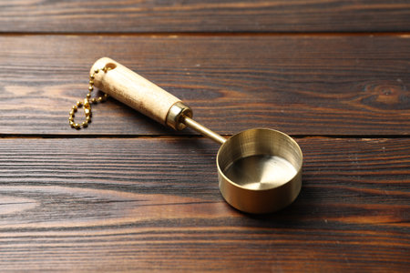 Golden scoop on wooden table, closeup. Kitchen utensilの写真素材