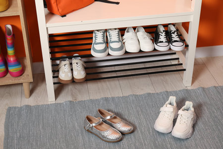 Shoe storage bench with different children's footwear indoorsの写真素材