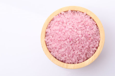 Pink sea salt in wooden bowl on white background, top viewの写真素材