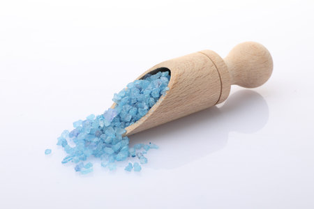 Blue sea salt in wooden scoop on white backgroundの写真素材