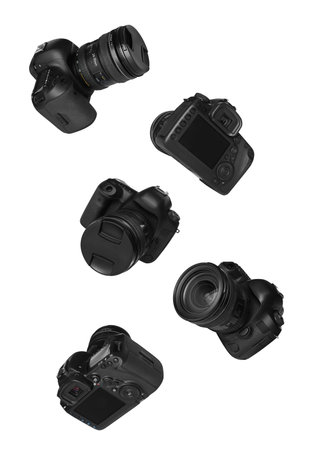 Photo cameras flying in air on white background