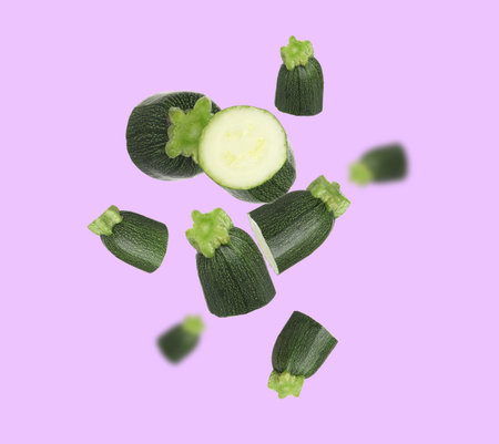 Zucchini pieces falling against violet background. Fresh vegetablesの写真素材