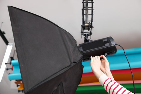 Woman with professional lighting equipment in photo studio, closeupの写真素材