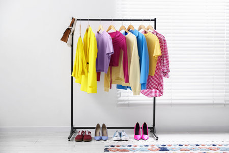 Different stylish clothes hanging on rack, bags and shoes indoorsの写真素材