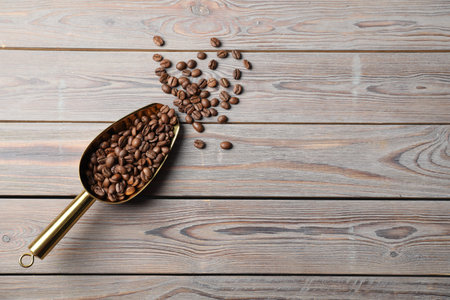 Pile of coffee beans and metal scoop on wooden table, flat lay. Space for textの写真素材