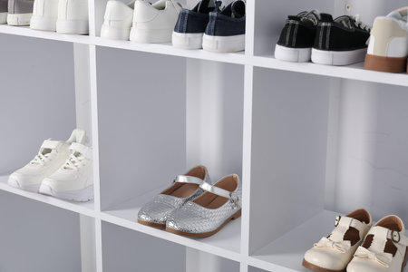 Different stylish children's shoes on shelving unit indoors, closeupの写真素材
