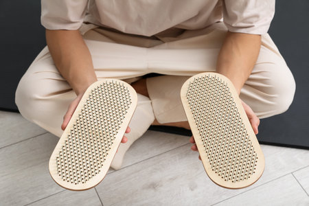 Young man with sadhu boards sitting on yoga mat at home, closeup