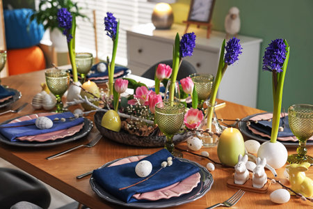 Easter celebration. Festive table setting with flowers and painted eggs indoors