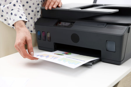 Woman using printer at white table indoors, closeup