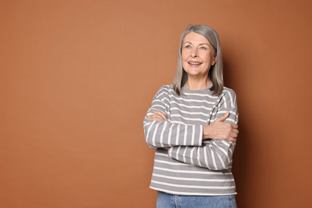 Portrait of beautiful senior woman on brown background. Space for text