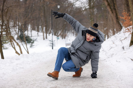 Young man falling on slippery pathway covered in ice outdoors, space for textの写真素材