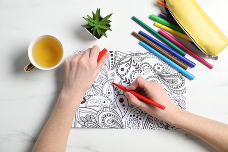 Woman coloring picture with felt tip pen at white table, top viewの写真素材