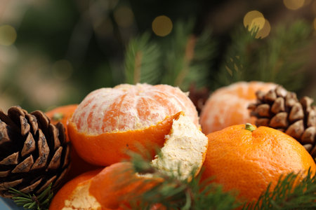 Ripe tangerines, cones and fir tree branches on blurred background, closeup. Bokeh effectの写真素材