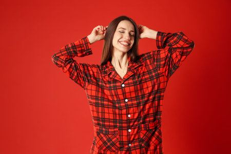 Happy woman in stylish pajamas on red backgroundの写真素材