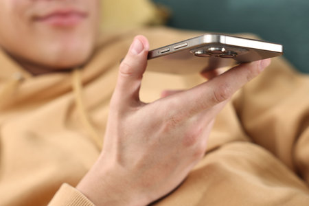 Man sending voice message via smartphone at home, closeup