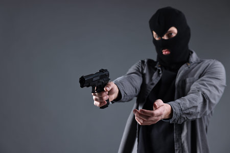 Dangerous criminal holding gun on dark gray background, space for text.の写真素材