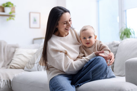 Mother with her cute baby boy on sofa at home