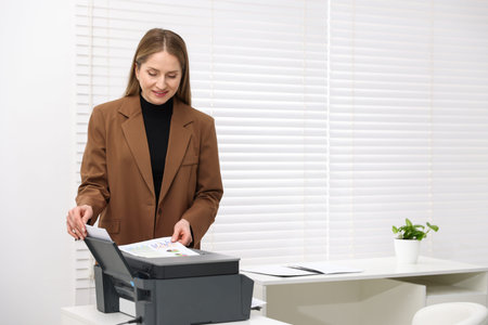 Smiling woman using printer at white desk in office