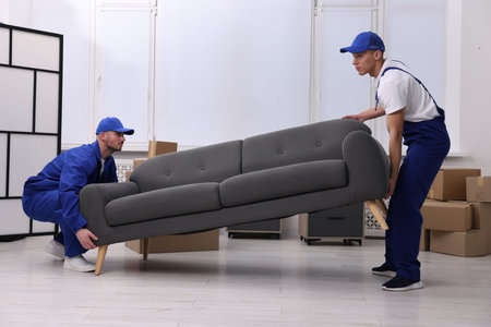 Two mover service workers carrying sofa indoorsの写真素材