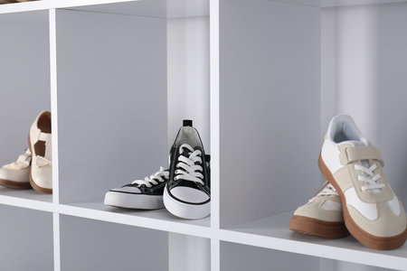 Different stylish children's shoes on shelving unit indoors, closeupの写真素材