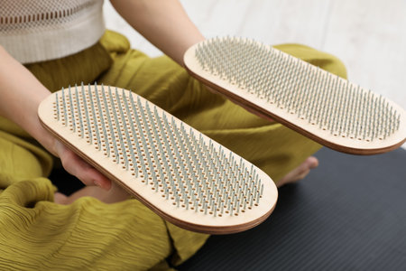 Young woman with boards sitting on yoga mat at home, closeup