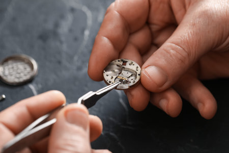 Senior man fixing mechanism of vintage wrist watch at black table, closeupの写真素材