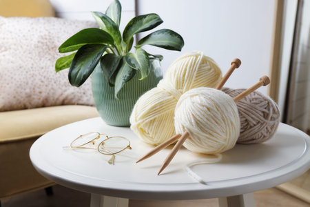 Knitting yarns, needles, glasses and houseplant on white table at home, closeupの写真素材