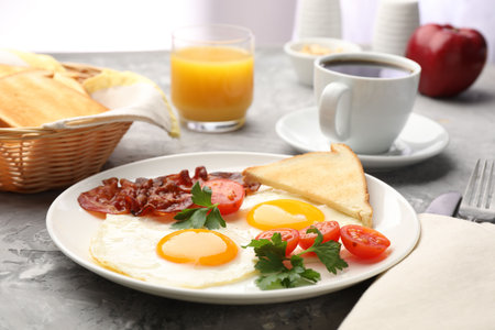 Delicious breakfast with fried eggs and bacon served on textured gray table, closeup