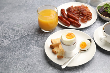 Tasty breakfast with hard boiled egg served on gray table, closeup