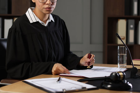 Judge stamping document at wooden desk indoors
