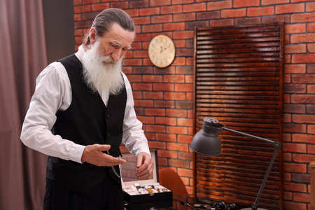 Senior man with vintage pocket watch indoorsの写真素材