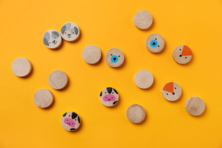 Wooden pieces with animals of children's game on yellow background, flat lay