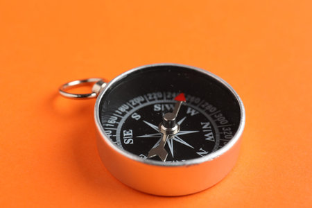 One compass on orange background, closeup view