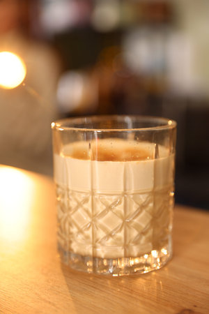 Glass of aromatic coffee on wooden table in cafe, closeup