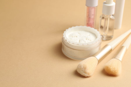 Different cosmetic products and makeup brushes on beige background, closeup. Space for text