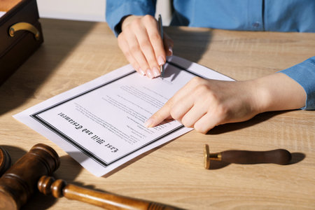 Woman signing Last Will and Testament at wooden table indoors, closeup