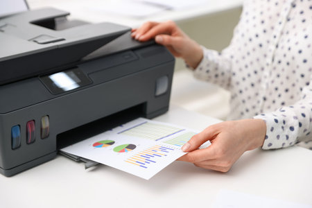 Woman using printer at white table indoors, closeup