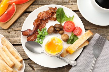 Tasty breakfast with soft boiled egg and bacon served on wooden table, flat lay