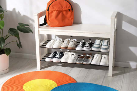 Shoe storage bench with different children's footwear, backpack and houseplant indoorsの写真素材