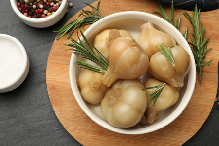 Pickled garlic in bowl and spices on black table, flat layの写真素材
