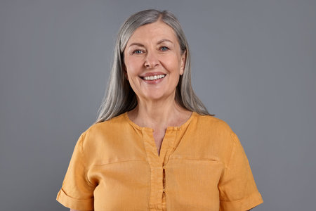Portrait of beautiful senior woman on gray background