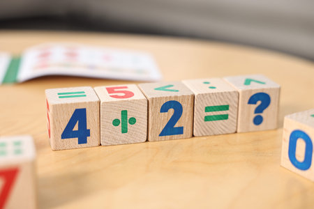Wooden cubes with mathematical formula on table indoors, closeup