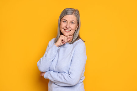 Portrait of beautiful senior woman on yellow backgroundの写真素材
