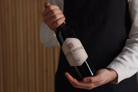 Professional sommelier with bottle of red wine indoors, closeupの写真素材