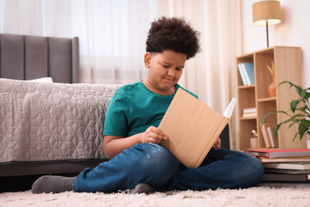 Boy reading book on floor at home