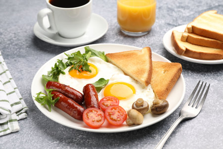 Delicious breakfast with fried eggs and sausages served on gray table, closeup