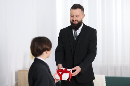 Cute boy greeting his father with gift at homeの写真素材